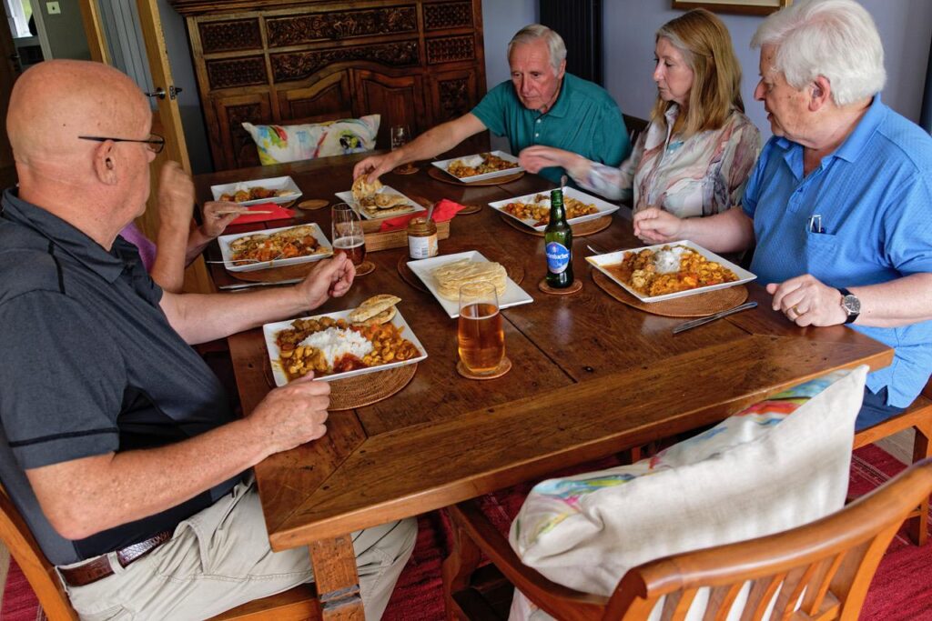 Five people sitting at a table with plates of food and drinks